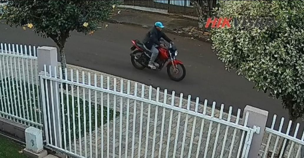 Câmera de segurança registrando o momento do furto de uma motocicleta vermelha em frente a uma residência no Jardim Santa Maria, Toledo.