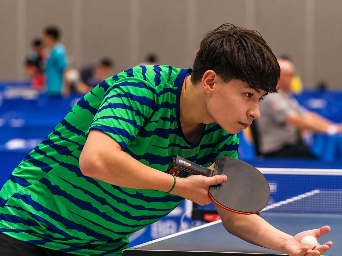 O jovem atleta Gustavo Avelar comemora a conquista do bicampeonato brasileiro escolar de tênis de mesa, segurando um troféu.