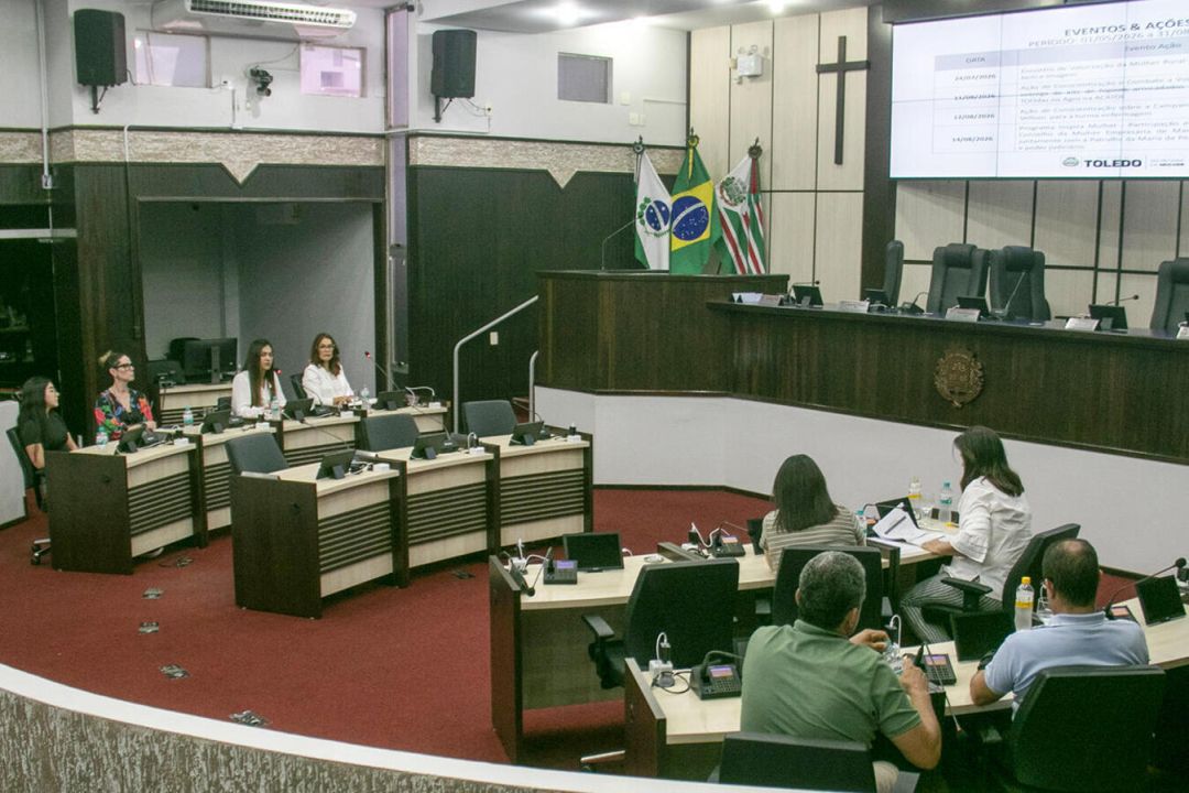 Apresentação de relatório da Secretaria da Mulher no plenário da Câmara de Vereadores de Toledo com autoridades e equipe técnica